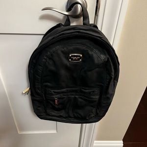 Michael Kors black nylon backpack with gold hardware zip front.